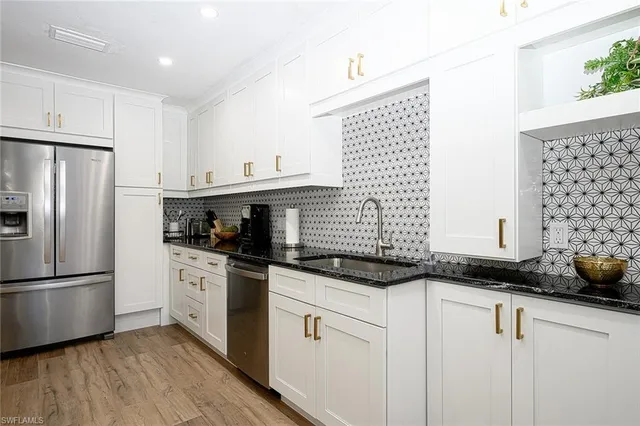 a kitchen with granite countertop a sink stainless steel appliances and cabinets