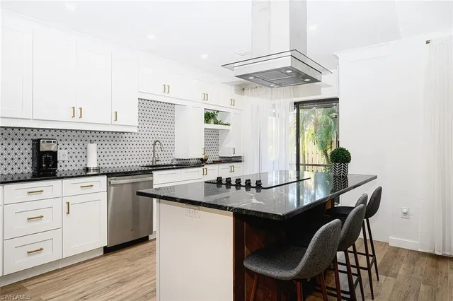a kitchen with granite countertop a sink chairs and cabinets