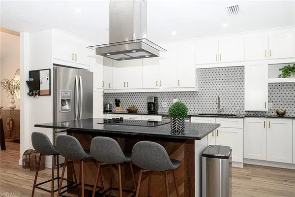 a kitchen with stainless steel appliances granite countertop a dining table chairs stove a refrigerator and chandelier