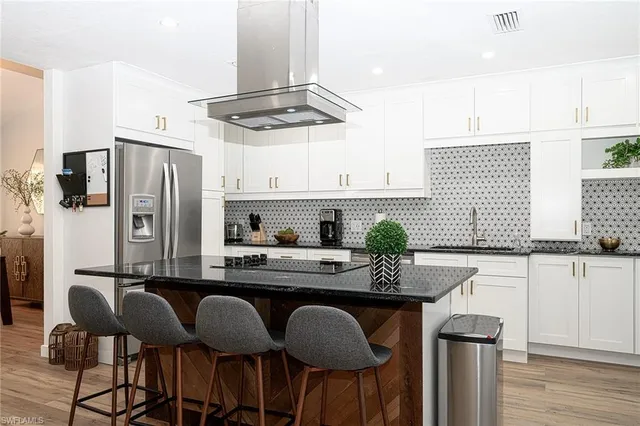 a kitchen with stainless steel appliances granite countertop a dining table chairs stove a refrigerator and chandelier
