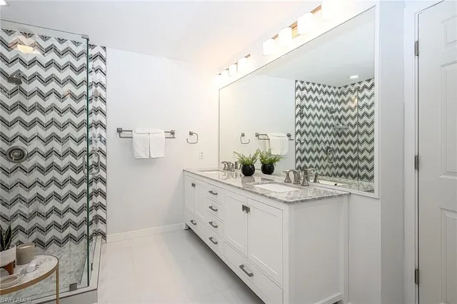 a bathroom with a granite countertop sink a mirror and shower