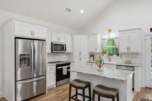 a kitchen with kitchen island white cabinets and stainless steel appliances