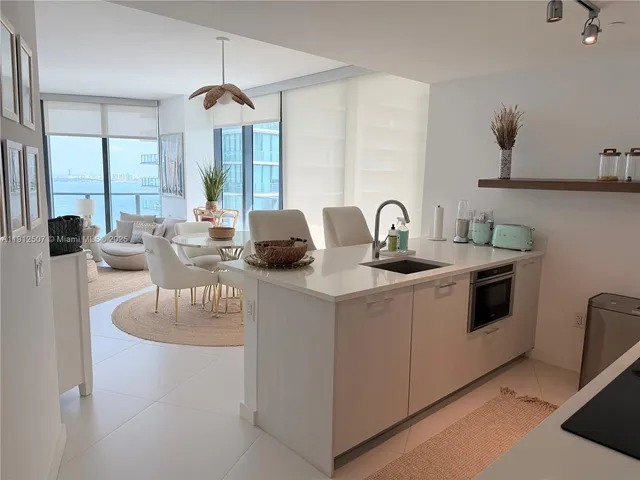 a kitchen with a stove a sink and a dining table with garden view