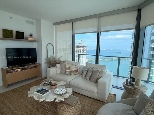 a living room with furniture a flat screen tv and a large window