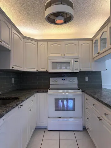a kitchen with granite countertop white cabinets and stainless steel appliances