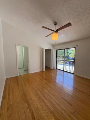 a view of empty room with wooden floor and fan