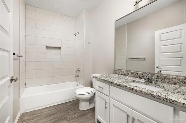 a bathroom with a granite countertop toilet a sink and bathtub