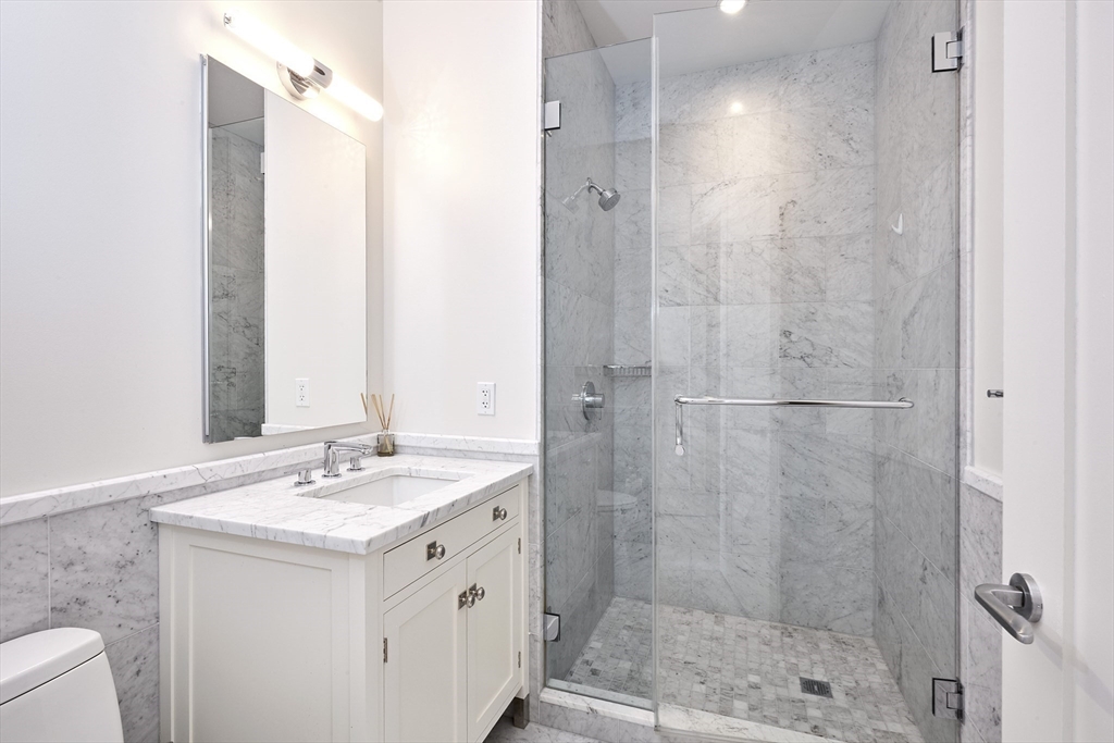 1 Franklin Street, Unit PH1B Boston, MA 02110 - Photo 21 of 42 a bathroom with a shower sink vanity and mirror
