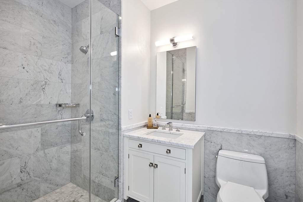 1 Franklin Street, Unit PH1B Boston, MA 02110 - Photo 29 of 42 a bathroom with a toilet sink vanity and mirror