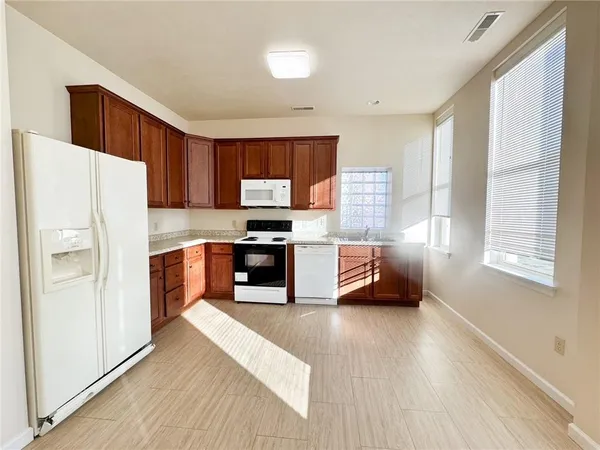 a kitchen with granite countertop a refrigerator a sink a stove top oven a cabinetry and a potted plant