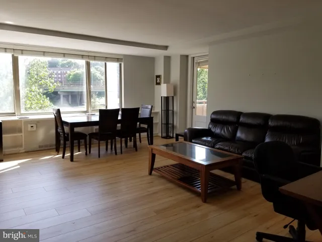 a living room with furniture and wooden floor to ceiling windows