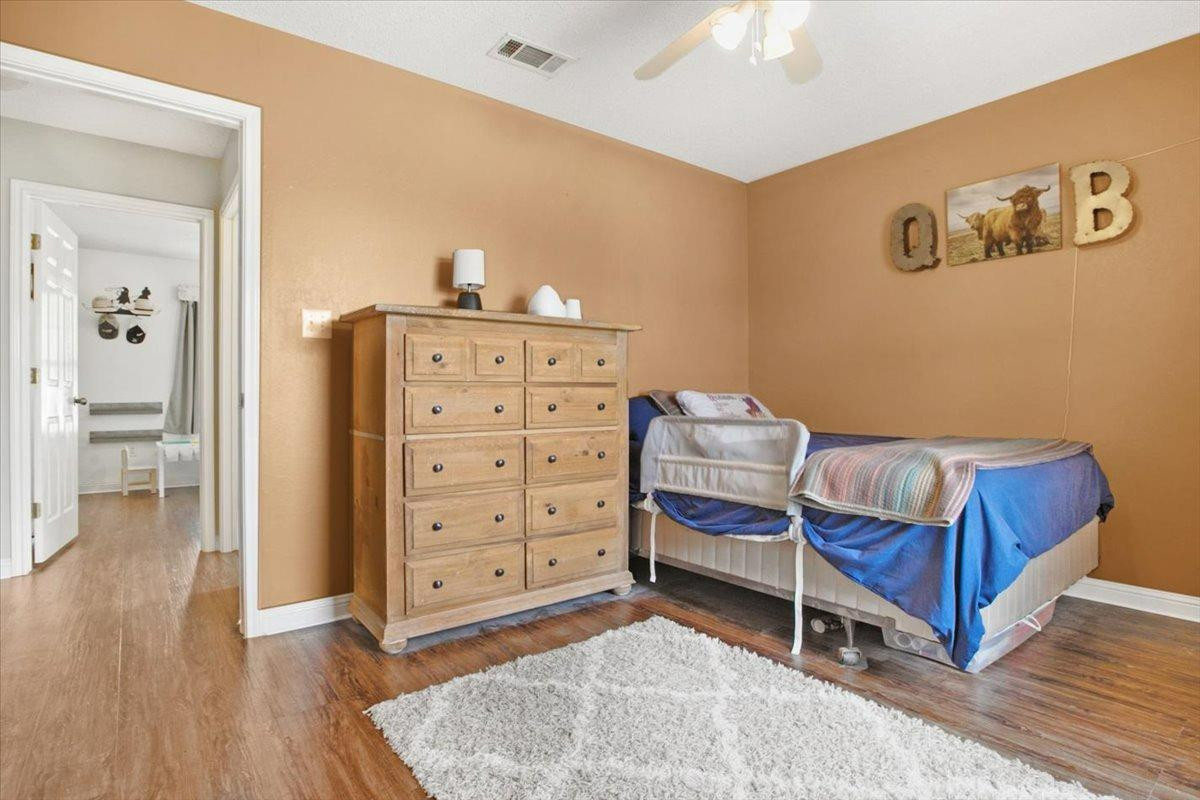 1703 Owl Road Lubbock, TX 79407 - Photo 17 of 33 a bedroom with a chair and wooden floor