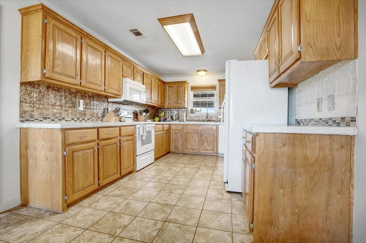 1703 Owl Road Lubbock, TX 79407 - Photo 10 of 33 a kitchen with stainless steel appliances granite countertop a refrigerator a sink dishwasher and white cabinets with wooden floor