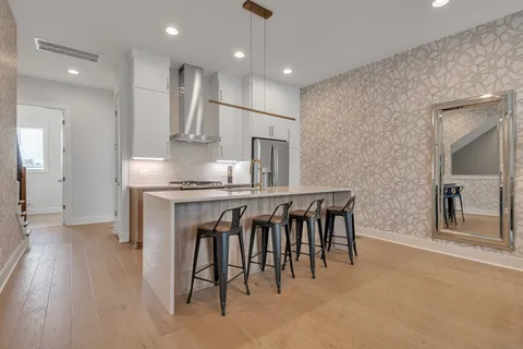 an open kitchen with refrigerator and wooden floor