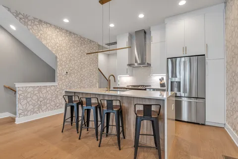 a kitchen with stainless steel appliances granite countertop a table chairs sink and refrigerator