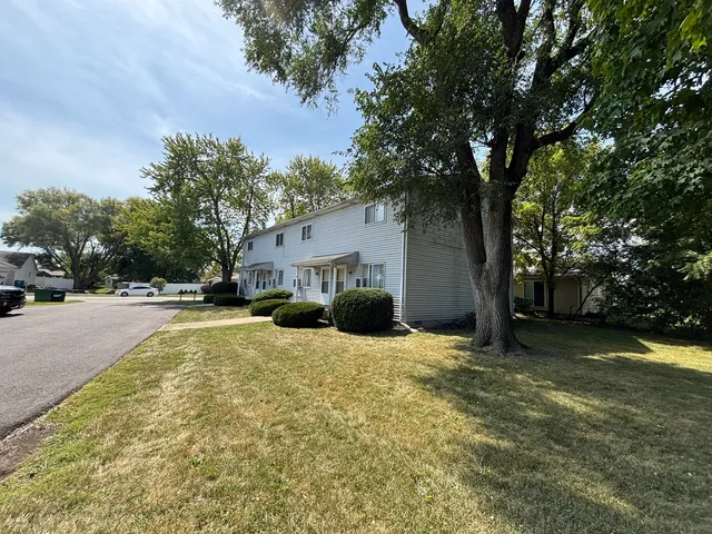 a view of a house with a large tree and a yard