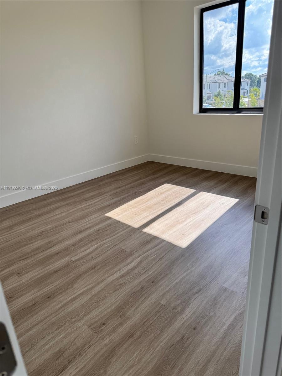 18932 Southwest 344th Terrace, Unit 18932 Homestead, FL 33034 - Photo 12 of 18 an empty room with wooden floor and windows