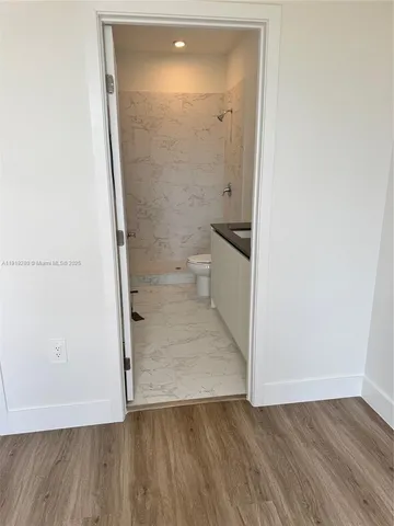 an empty room with wooden floor and toilet