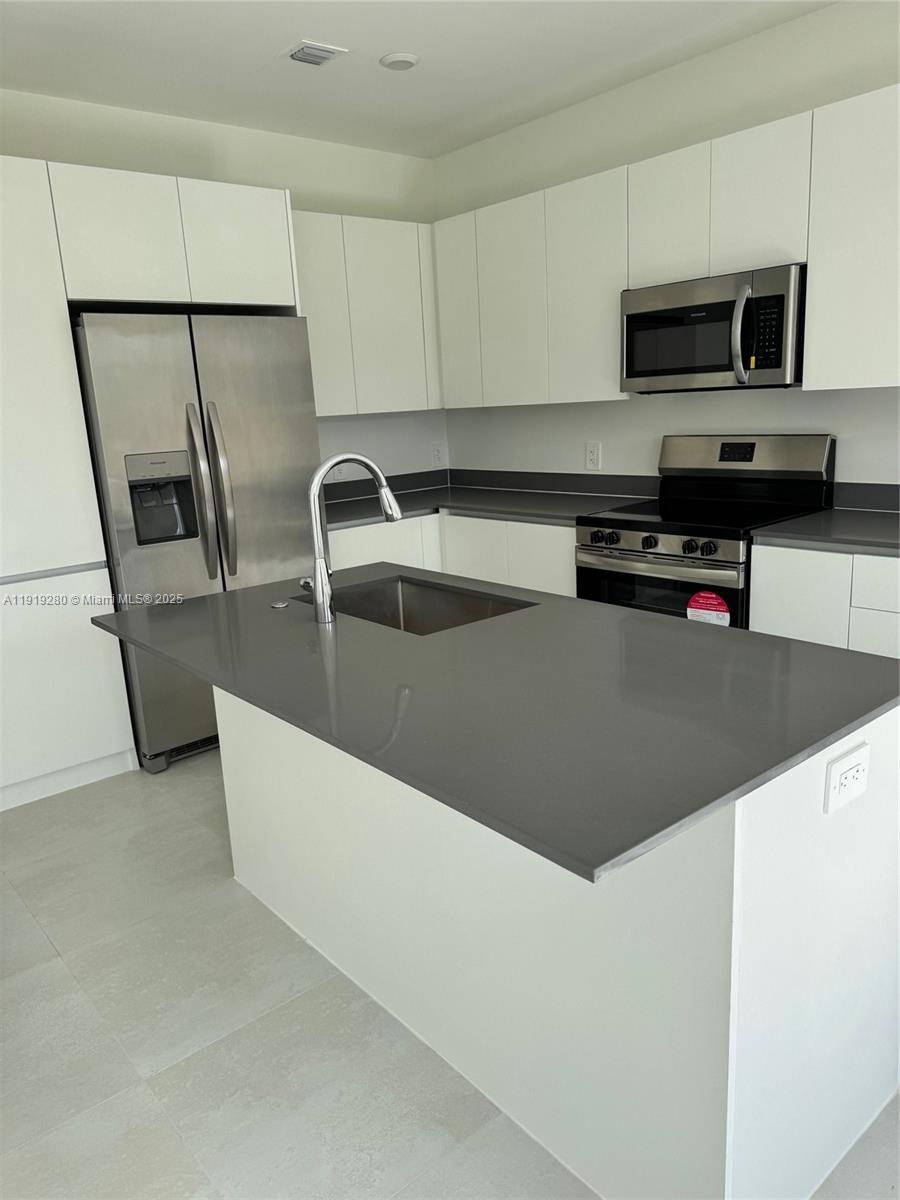 18932 Southwest 344th Terrace, Unit 18932 Homestead, FL 33034 - Photo 5 of 18 a kitchen with stainless steel appliances granite countertop a sink a stove top oven a refrigerator and a granite counter tops