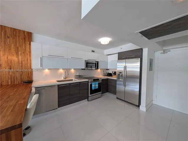 a large kitchen with a large counter top stainless steel appliances and wooden cabinets