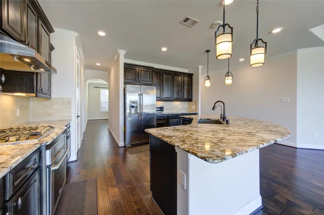 a kitchen with stainless steel appliances granite countertop a sink a stove and a wooden floors