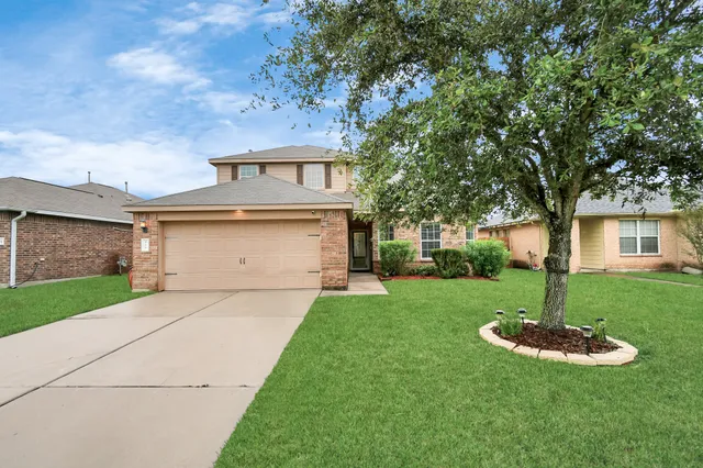 a front view of a house with a yard fire pit and large tree