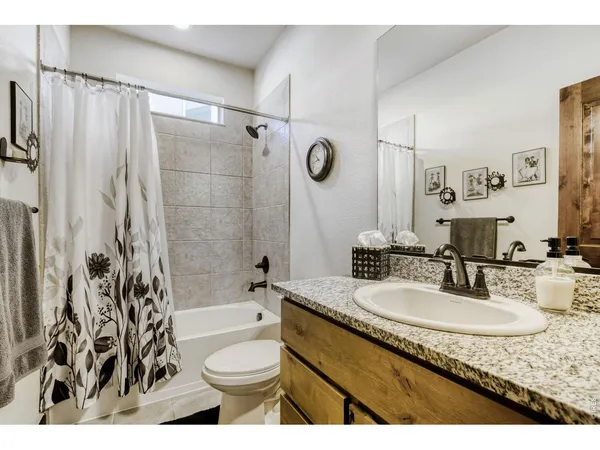 a bathroom with a granite countertop sink toilet a mirror a bathtub and shower