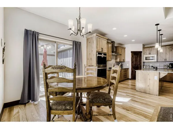 a dining room with kitchen island stainless steel appliances furniture a chandelier and kitchen view