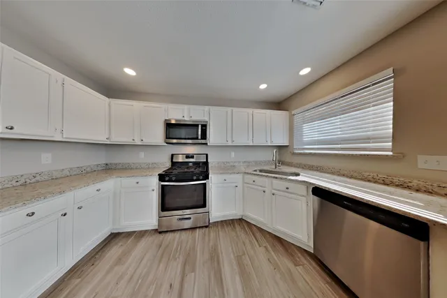 a kitchen with granite countertop cabinets stainless steel appliances and a sink