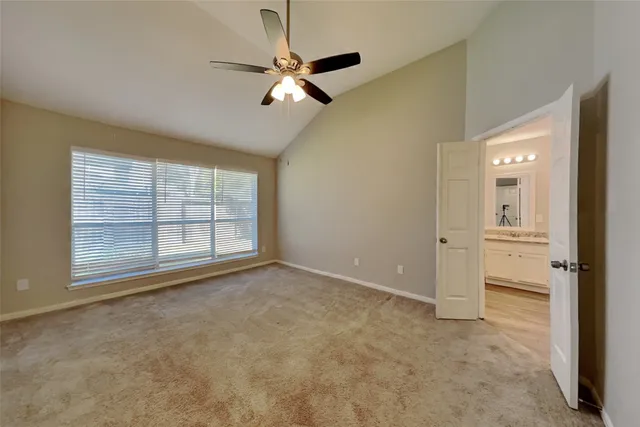 an empty room with chandelier fan and windows