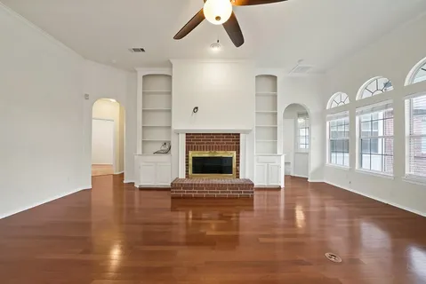 an empty room with windows fireplace and wooden floor