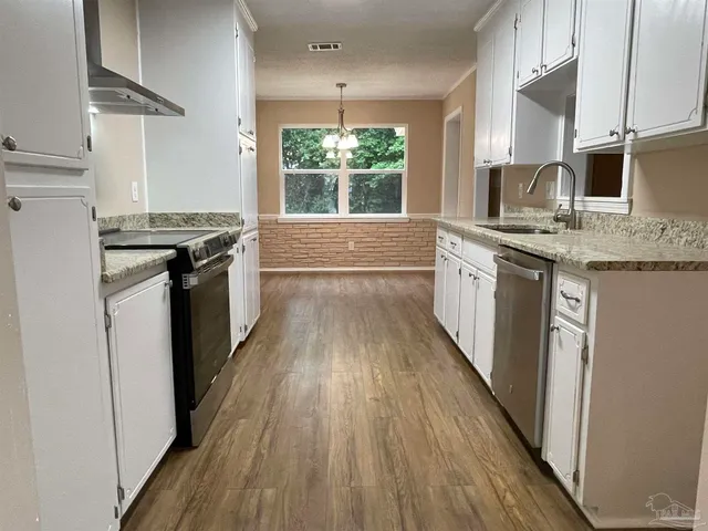 a kitchen with stainless steel appliances hardwood floor sink stove and wooden cabinets