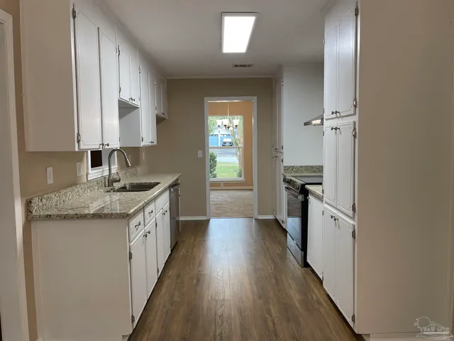 a kitchen with granite countertop a sink stove and refrigerator