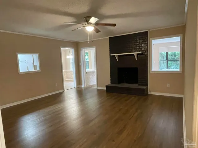 an empty room with wooden floor fireplace and windows