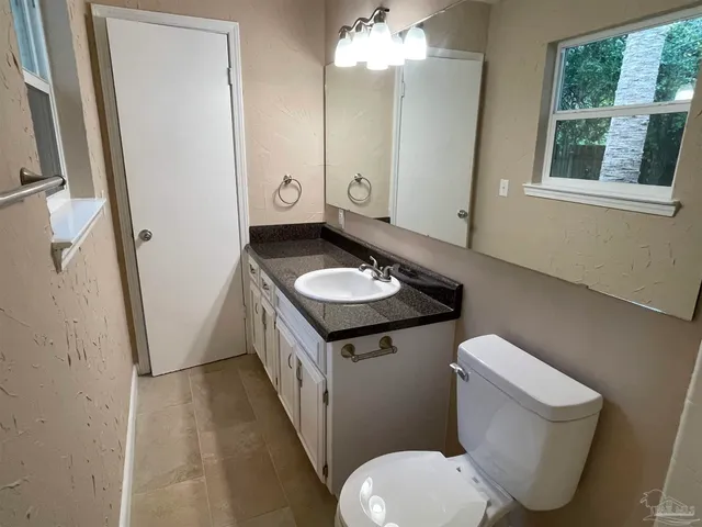 a bathroom with a granite countertop toilet sink and mirror