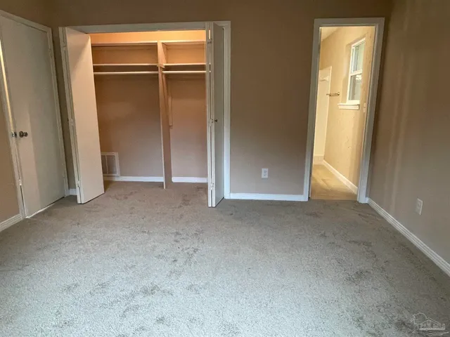 a view of an empty room with closet and a window