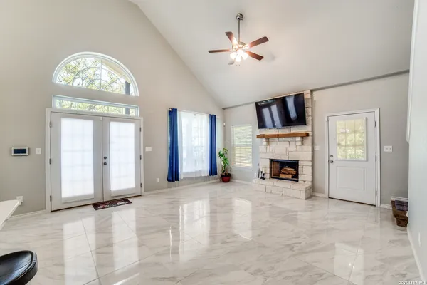 an empty room with windows fireplace and fans