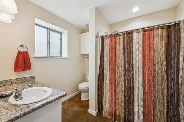 a bathroom with a sink a toilet and shower curtain