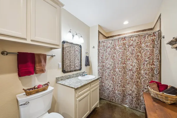 a bathroom with a granite countertop sink and a toilet