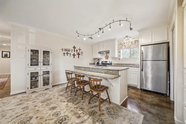 a kitchen with stainless steel appliances a refrigerator a stove a sink and a dining table