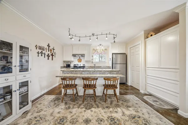 a dining room with stainless steel appliances kitchen island granite countertop a refrigerator and microwave