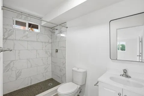 a bathroom with a toilet a sink a mirror and shower