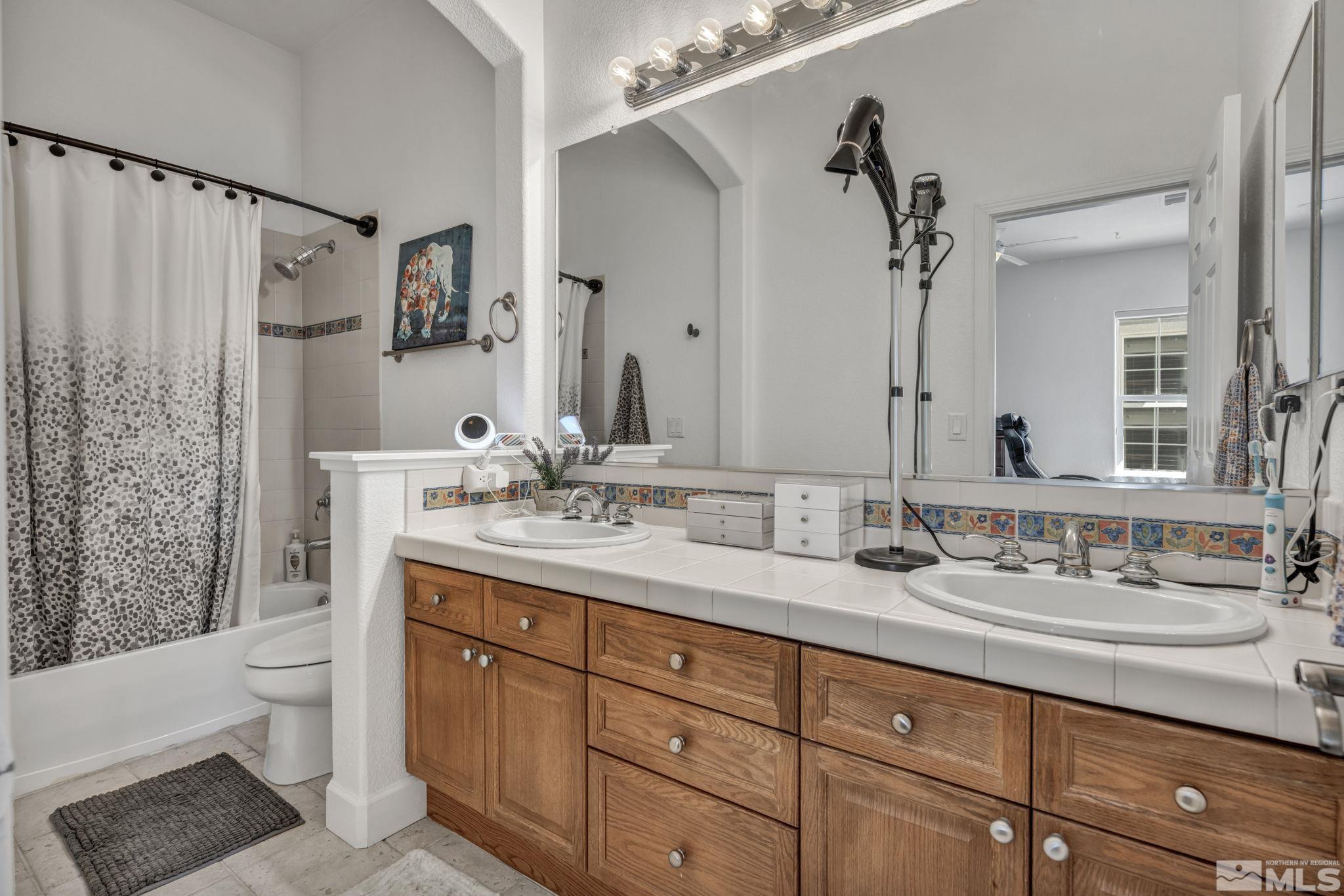 5544 New Mexico Court Reno, NV 89511 - Photo 18 of 39 a bathroom with double vanity sink a toilet a mirror and shower