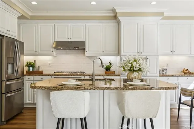 a kitchen with stainless steel appliances granite countertop a stove a refrigerator a white table and chairs