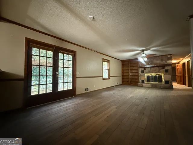 a view of empty room with wooden floor and fan