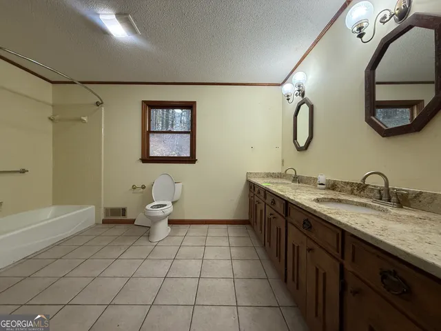 a spacious bathroom with a double vanity sink toilet and a mirror