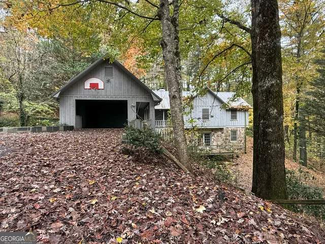 a front view of a house with a yard and large tree