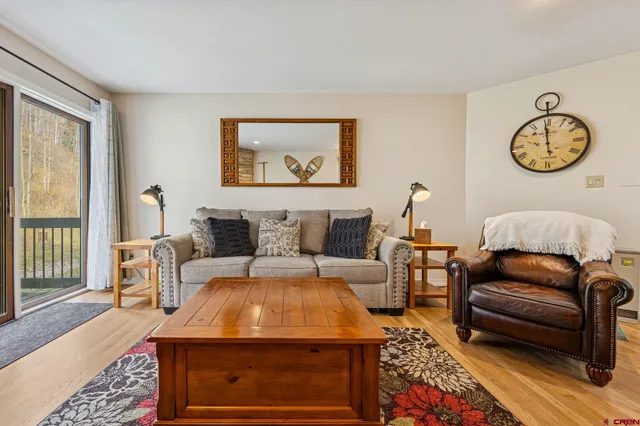 a living room with furniture a clock on wall and a window