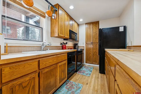 a kitchen with stainless steel appliances granite countertop a sink a stove and a wooden floors