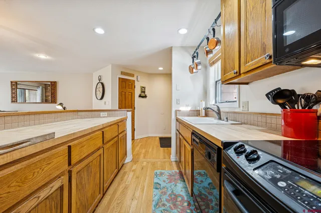 a kitchen with stainless steel appliances granite countertop a sink a stove and a wooden floors